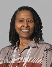 Gheretta is smiling and wearing a brown plaid shirt.