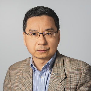 Steven is smiling and wearing a brown, checkered blazer.